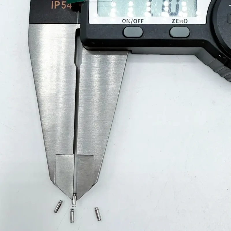 Stainless steel micro pins, precision CNC machined, being measured by a digital caliper, ideal for high - tech electronics.