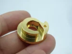 Gold plated CNC machined precision component held in hand to show size