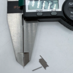 Small precision stainless steel pin on fingertip displaying size